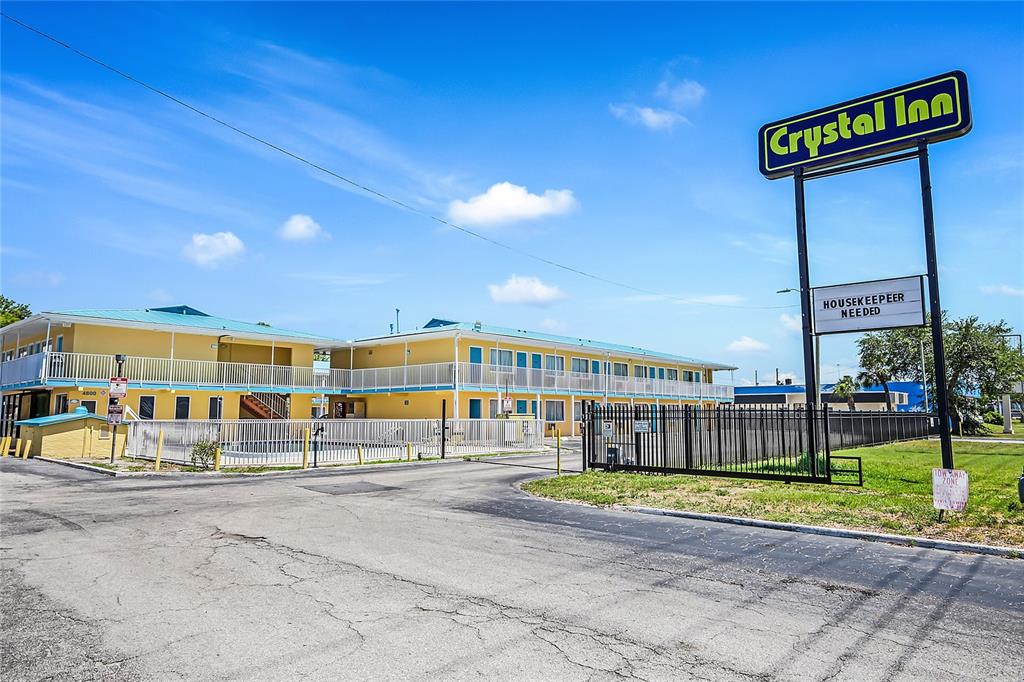 A yellow two-story motel building stands behind a black metal fence with a prominent sign — 4600 34TH STREET S, ST PETERSBURG, FL