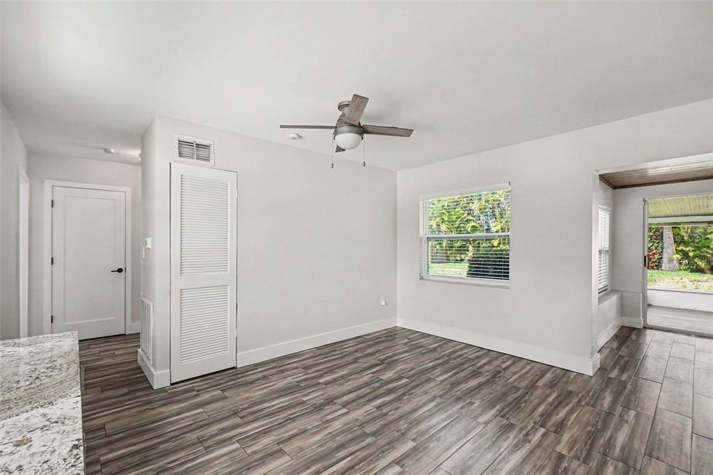 An empty room with wood-look tile flooring, a ceiling fan, and a sliding glass door — 2009 TARPON ROAD, PALMETTO, FL