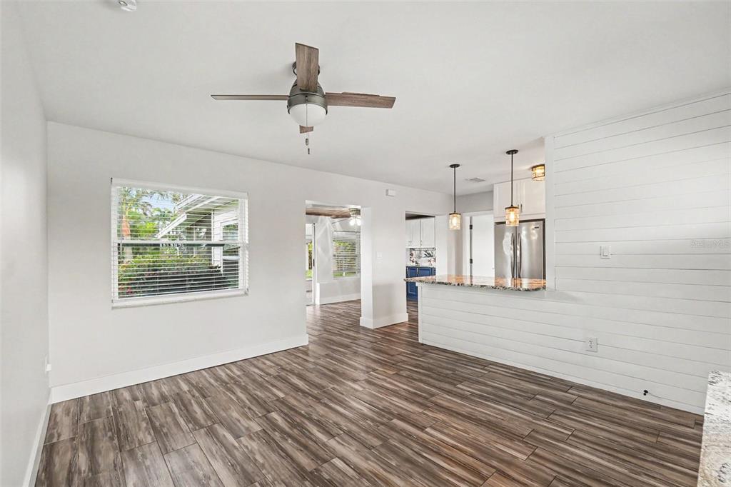 A living area with wood-look tile floors, a ceiling fan, and a shiplap kitchen peninsula — 2009 TARPON ROAD, PALMETTO, FL