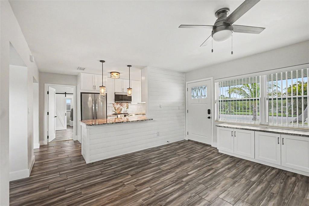 A kitchen and living area feature white shiplap walls, wood-look tile flooring, and white cabinetry — 2009 TARPON ROAD, PALMETTO, FL