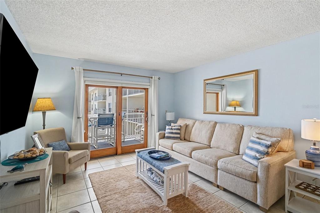 A living room features a beige sofa, armchair, coffee table, and sliding glass balcony doors — 4153 S ATLANTIC AVENUE UNIT 4160, NEW SMYRNA BEACH, FL