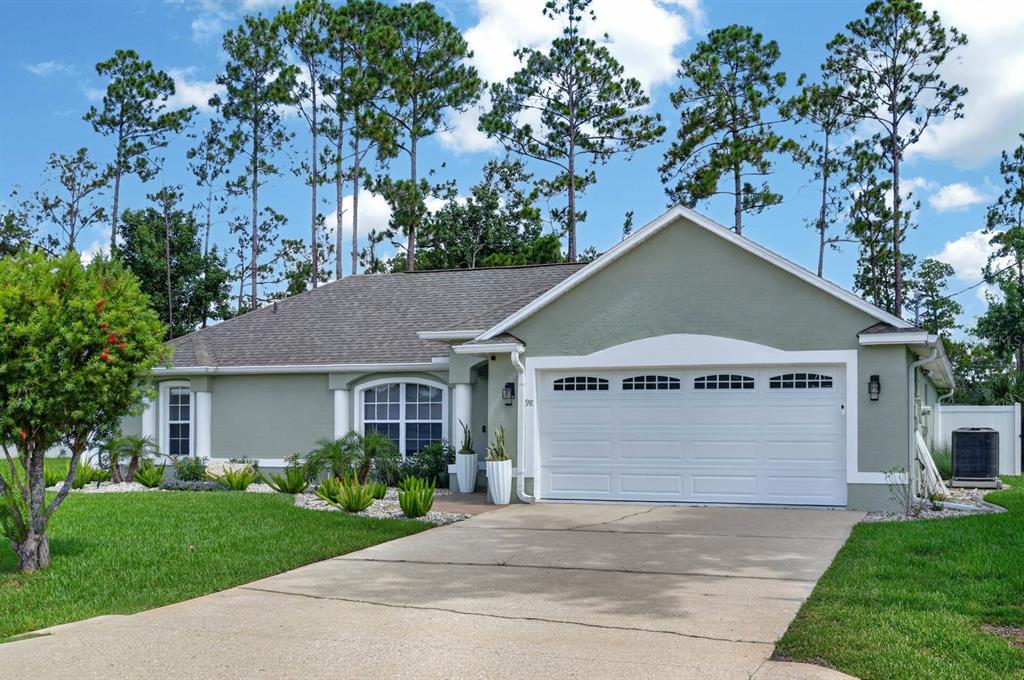 A single-story house with a green stucco exterior, a two-car garage, and a concrete driveway — 98 WESTGRILL DRIVE, PALM COAST, FL