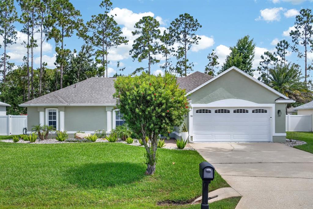 A single-story house with a green exterior, a two-car garage, and a landscaped front yard — 98 WESTGRILL DRIVE, PALM COAST, FL