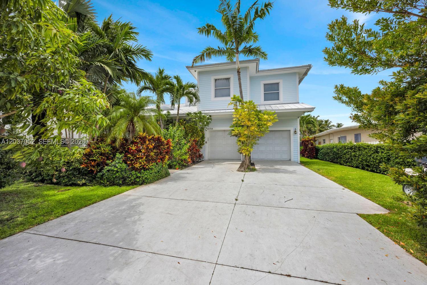 A two-story light blue house with a two-car garage and a concrete driveway — 1074 NE Little River Dr, Miami FL 33138, MIAMI, FL
