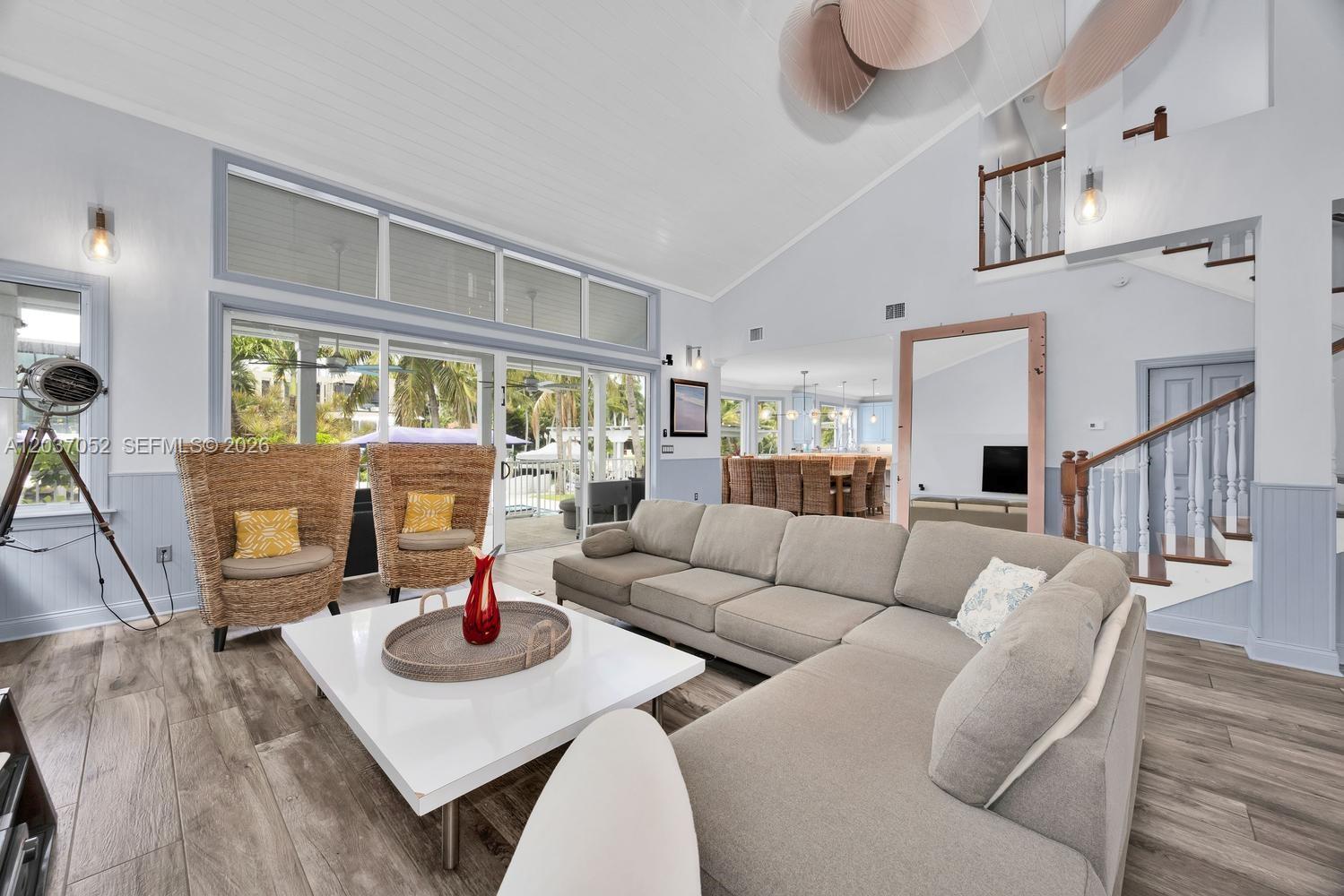 A living room features a large sectional sofa, two wicker chairs, and high vaulted ceilings — 1074 NE Little River Dr, Miami FL 33138, MIAMI, FL