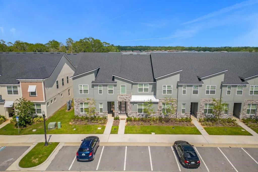 An exterior view of a multi-unit townhouse complex with gray siding and stone accents — 1676 TROPICAL PALMS CIRCLE, KISSIMMEE, FL