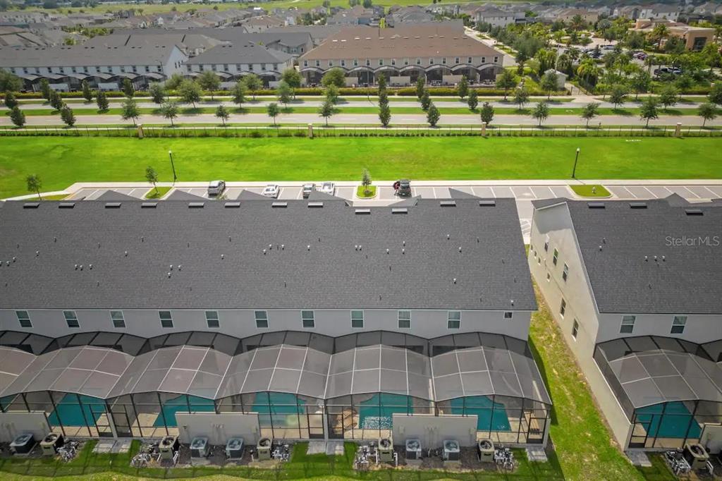 An aerial view shows a row of townhomes with screened-in pools and back patios — 1676 TROPICAL PALMS CIRCLE, KISSIMMEE, FL