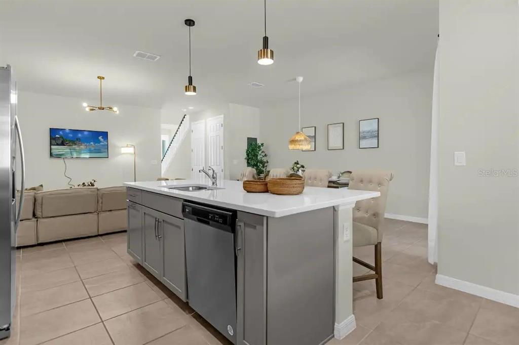 A kitchen island with a sink and dishwasher sits in front of a dining area — 1676 TROPICAL PALMS CIRCLE, KISSIMMEE, FL