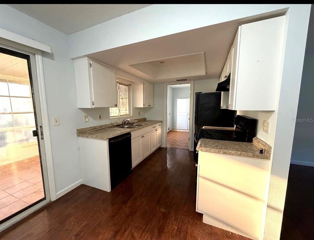 A kitchen with white cabinets, laminate countertops, dark appliances, and wood-look flooring — 11248 SW 76TH TERRACE, OCALA, FL