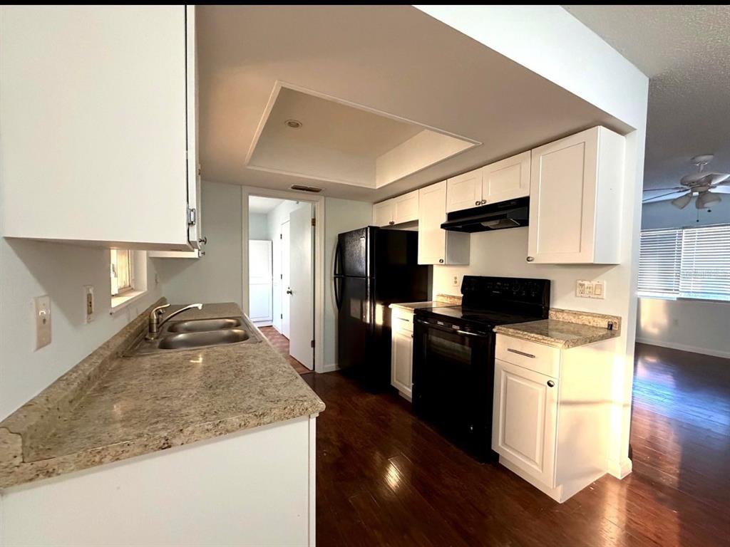 A kitchen features white cabinets, granite countertops, black appliances, and dark wood flooring — 11248 SW 76TH TERRACE, OCALA, FL