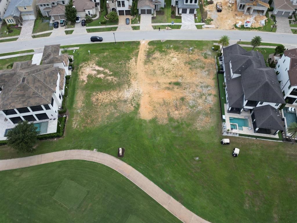 An aerial view shows a vacant residential lot situated between two large houses and a golf course — 16047 VETTA DRIVE, MONTVERDE, FL