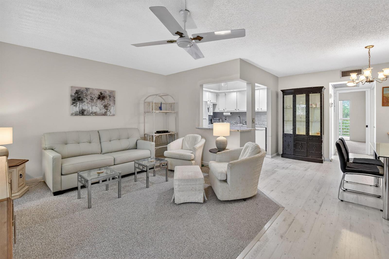 A living room with light-colored furniture, a gray area rug, and an open kitchen pass-through — 4038 Durham B, Deerfield Beach FL 33442, DEERFIELD BEACH, FL