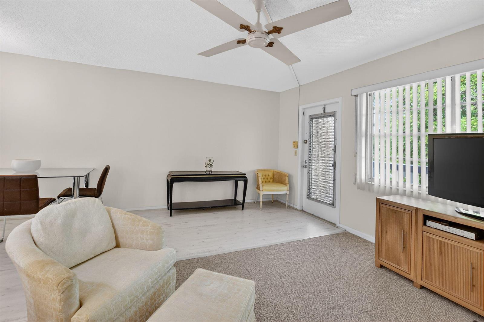 A living room features a ceiling fan, carpeted and wood-look flooring, and a glass door — 4038 Durham B, Deerfield Beach FL 33442, DEERFIELD BEACH, FL
