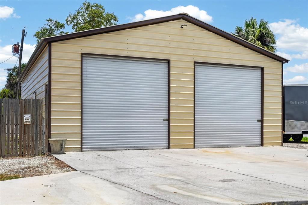 A detached metal garage with two roll-up doors sits on a concrete driveway — 1803 EVERGREEN DRIVE, EDGEWATER, FL