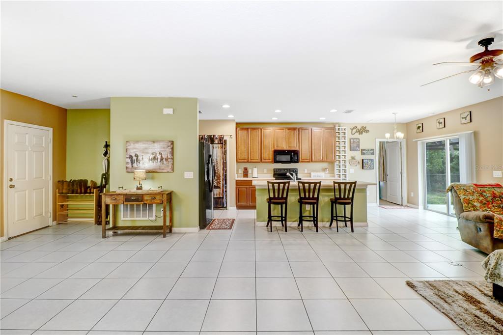 A covered front porch features a gray door, two black chairs, and a concrete walkway — 12152 LANDFAIR STREET, SPRING HILL, FL