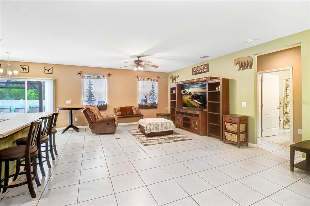 An open-concept kitchen with wooden cabinets and a breakfast bar overlooks a tiled living area — 12152 LANDFAIR STREET, SPRING HILL, FL