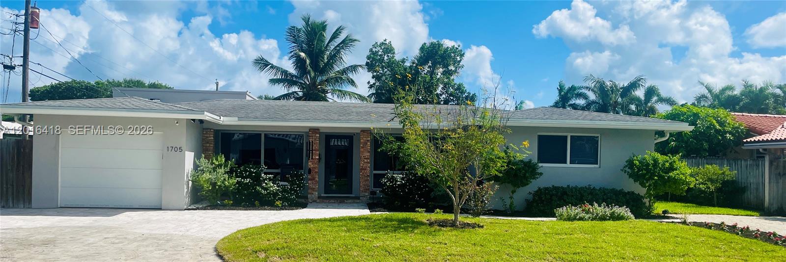 A single-story house with a white garage, gray exterior, and a front lawn — 1705 NE 24th St, Wilton Manors FL 33305, WILTON MANORS, FL
