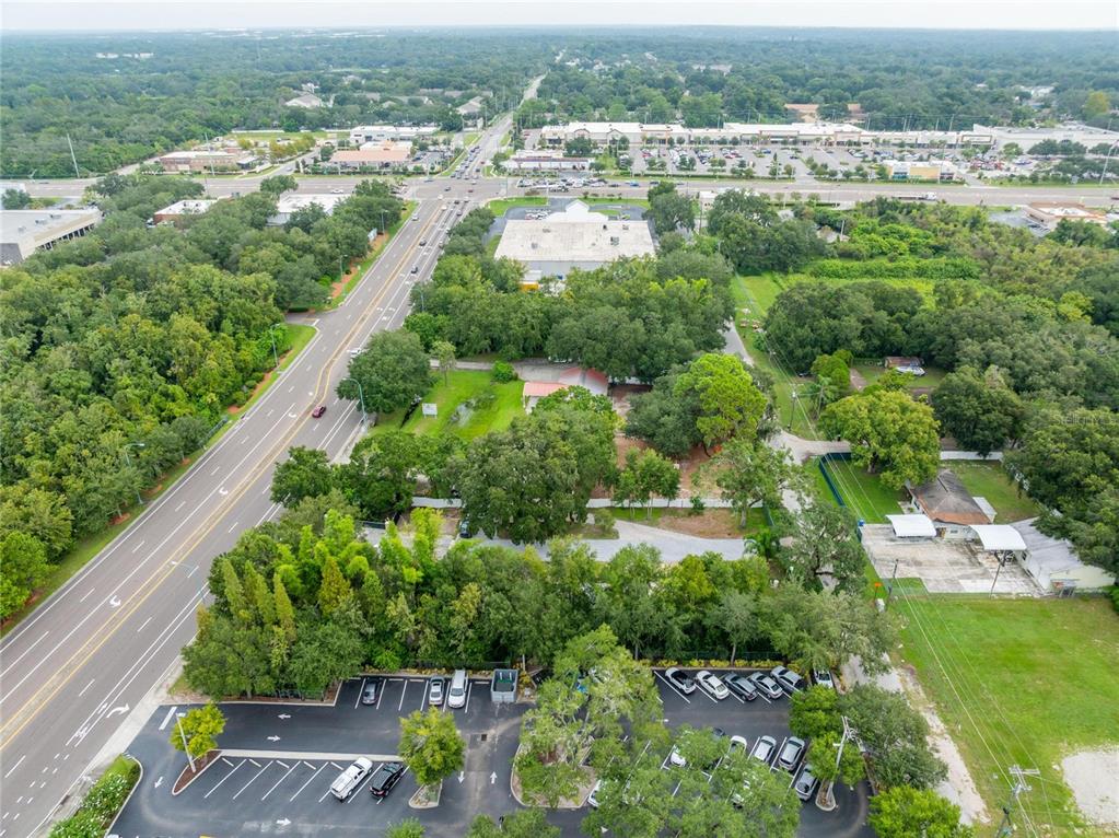 An aerial view shows a commercial building, a parking lot, and surrounding trees near a road — 201 S LAKEWOOD DRIVE, BRANDON, FL