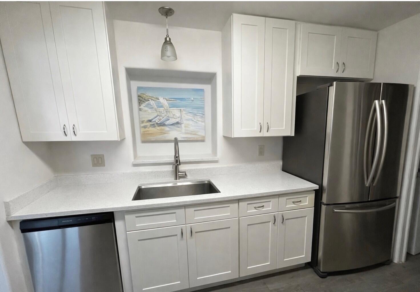 A kitchen with white cabinets, stainless steel appliances, a sink, and a beach-themed wall art — 4472 SE Alden Avenue, Stuart FL 34997, STUART, FL