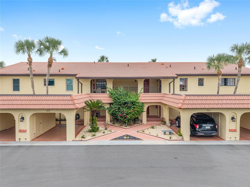 A two-story residential building features a tiled roof, covered carports, and a central landscaped courtyard — 362 NW 14TH PLACE UNIT 21, CRYSTAL RIVER, FL