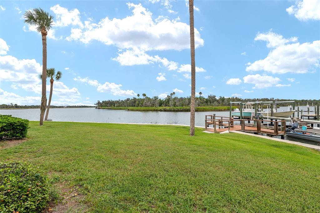 A grassy lawn leads to a wooden boat dock on a calm waterfront — 362 NW 14TH PLACE UNIT 21, CRYSTAL RIVER, FL