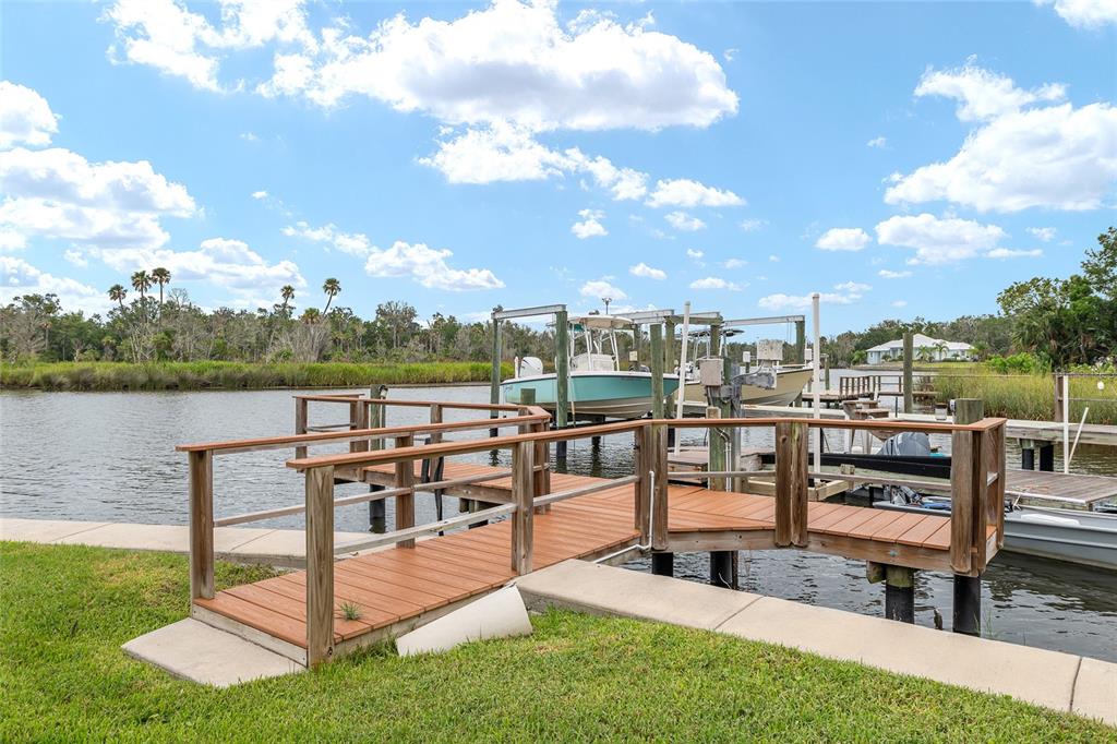 A wooden dock with a boat lift extends into a canal under a cloudy sky — 362 NW 14TH PLACE UNIT 21, CRYSTAL RIVER, FL