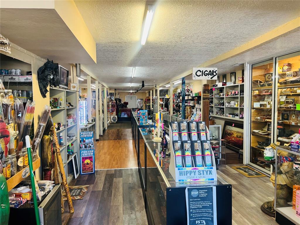 A retail store interior features glass display cases, shelves stocked with merchandise, and wood-look flooring — 215 W OAK STREET, ARCADIA, FL