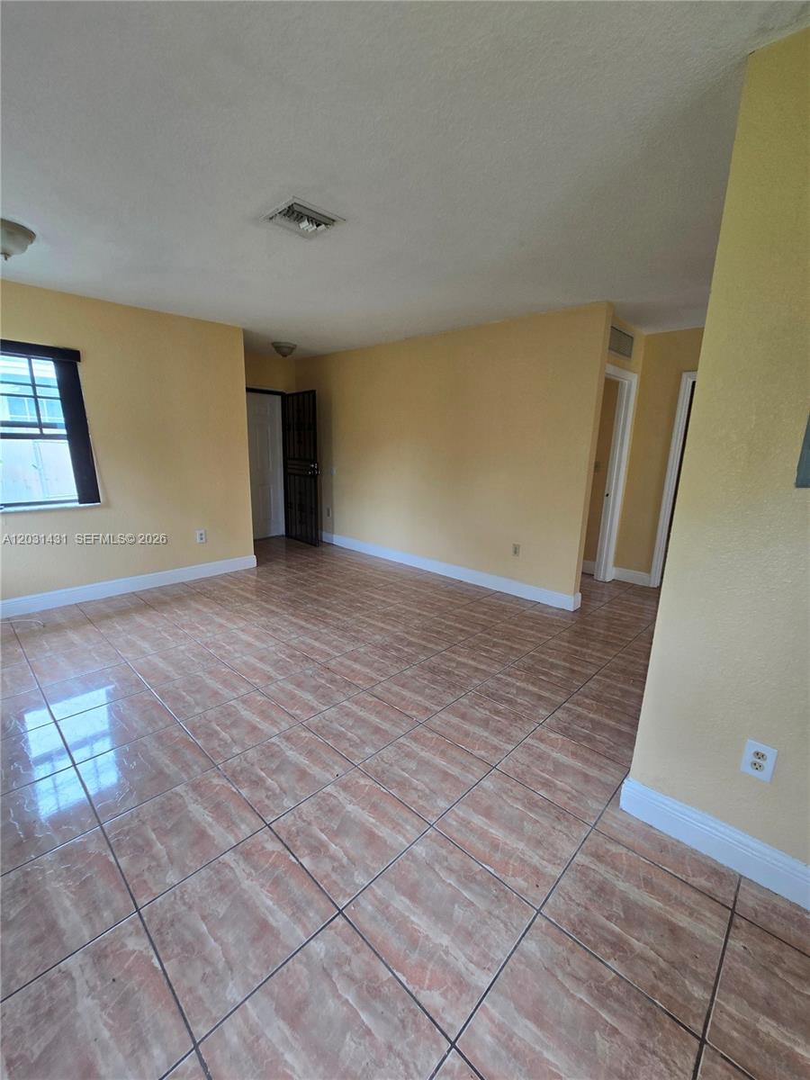 An empty room features yellow walls, tiled flooring, and a window with a black frame — 313 NW 97th St # 313, Miami FL 33150, MIAMI, FL