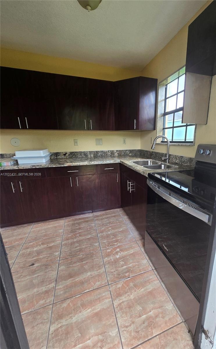 A kitchen features dark wood cabinets, granite countertops, a stainless steel sink, and tiled floors — 313 NW 97th St # 313, Miami FL 33150, MIAMI, FL
