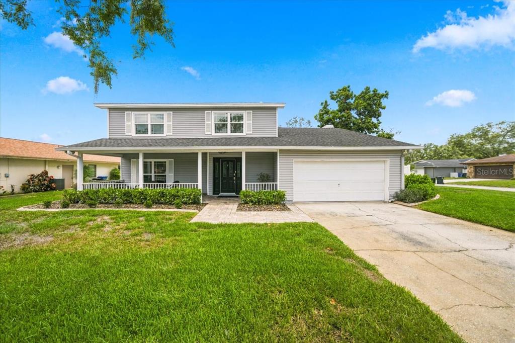 A two-story gray house with a front porch, attached garage, and a concrete driveway — 13101 BURNES LAKE DRIVE, TAMPA, FL