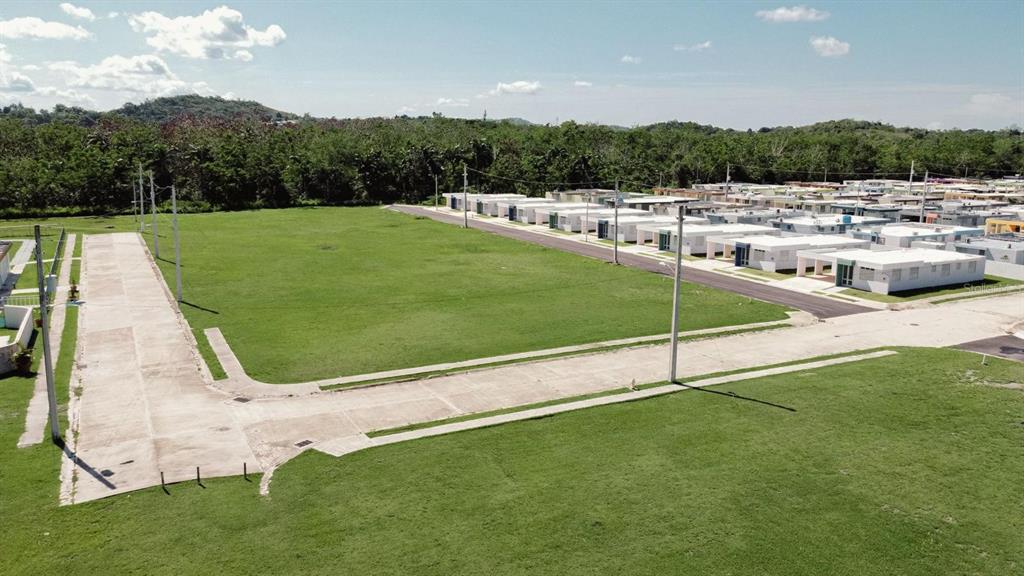 An aerial view shows a large, vacant grassy lot adjacent to a residential neighborhood — VEREDAS DEL MAR, CABO ROJO, PR
