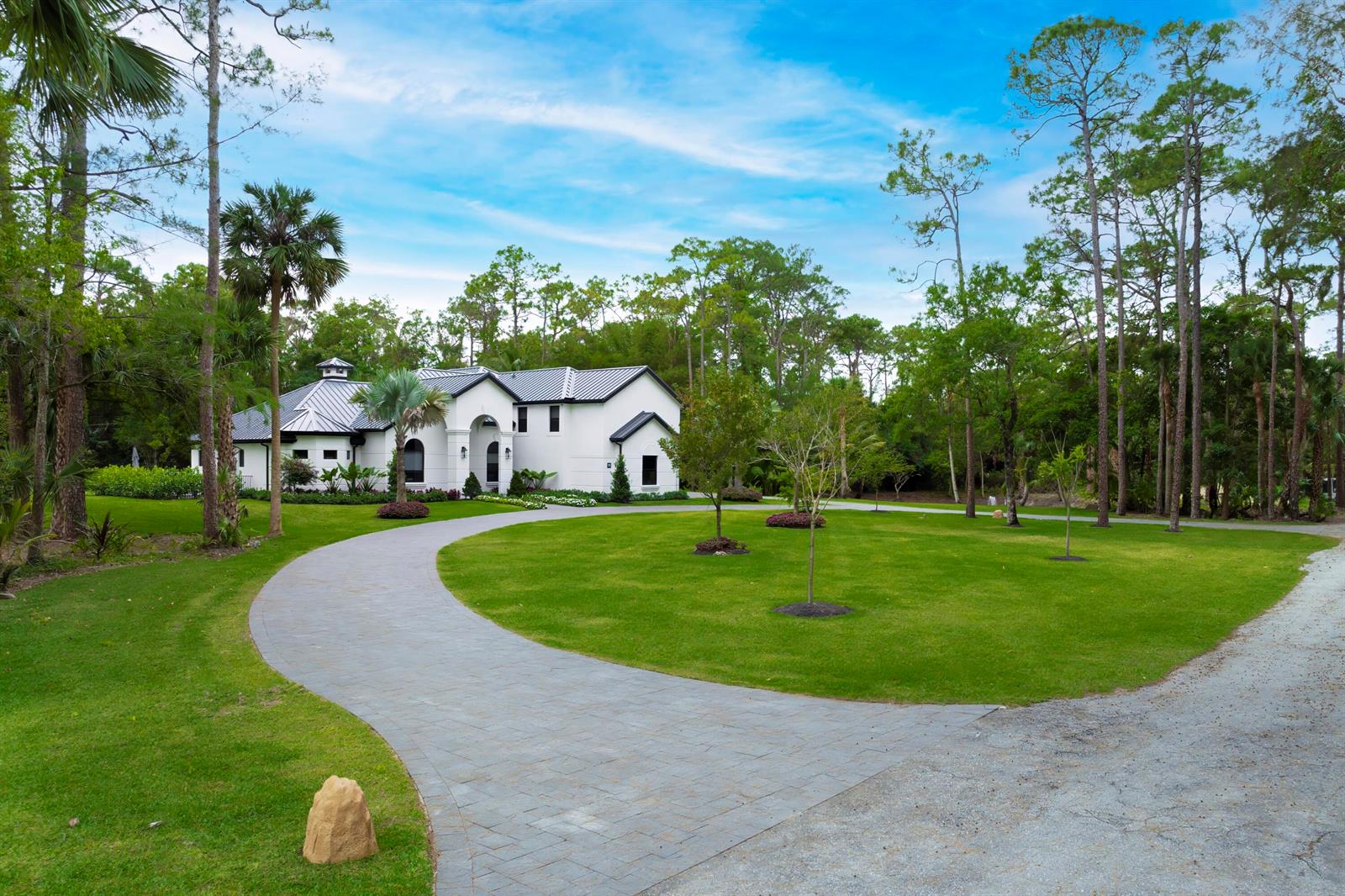 A white house with a dark metal roof sits at the end of a paved driveway — 1201 F Road, FL 33470, FL