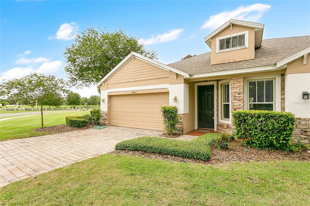 A single-story house with a tan garage, brick accents, and a small dormer window above — 34346 TUSCANY AVENUE, SORRENTO, FL