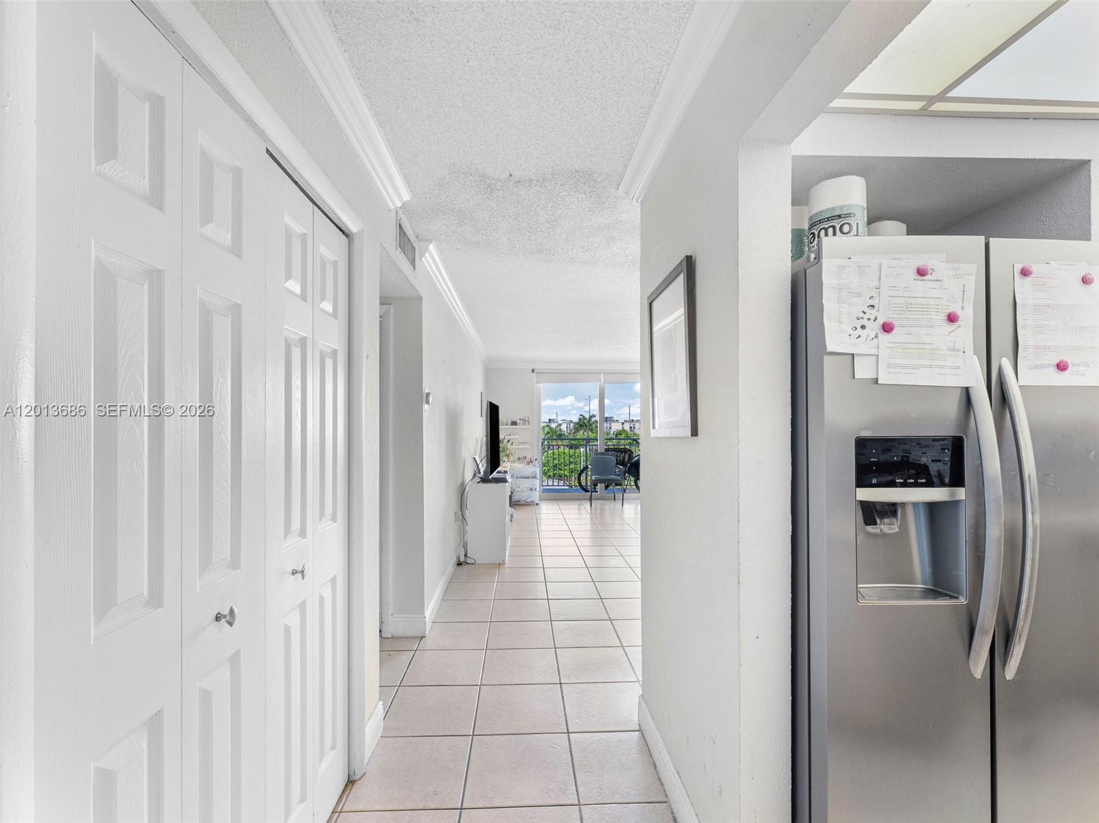 A tiled hallway leads from a kitchen area toward a living room with a balcony — 6950 Miami Gardens Dr # 506, Hialeah FL 33015, HIALEAH, FL