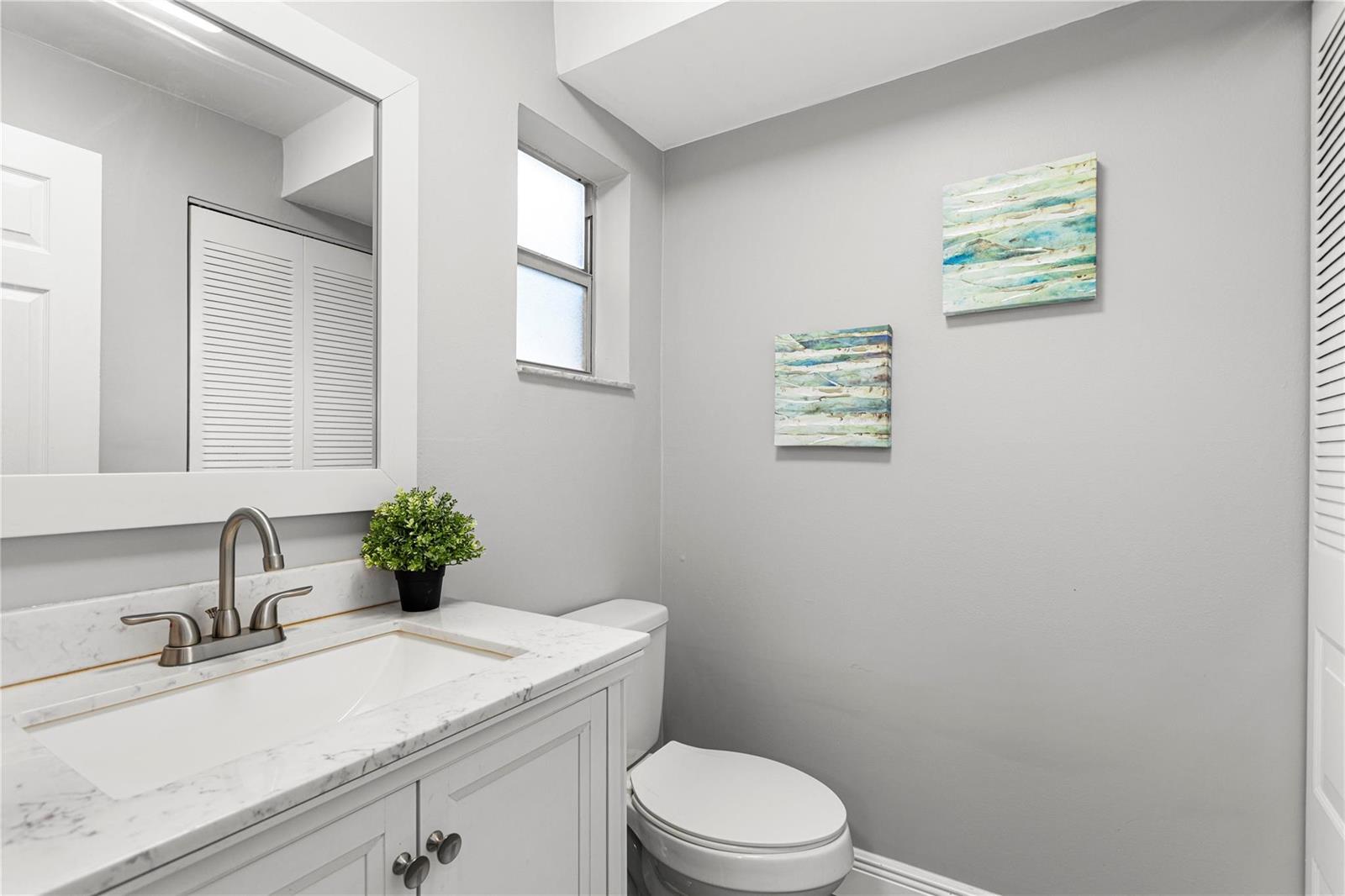 A bathroom features a white vanity with a marble countertop, a toilet, and wall art — 9700 Sunrise Lakes Boulevard # 101, Sunrise FL 33322, SUNRISE, FL