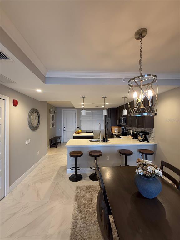 A kitchen with a breakfast bar, dark cabinets, and a dining area with tile flooring — 16300 COUNTY ROAD 455 UNIT 604, MONTVERDE, FL