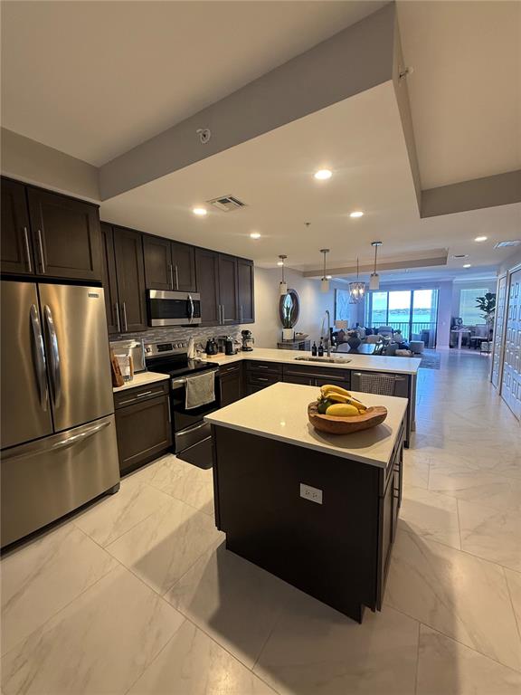 A kitchen with dark cabinets, stainless steel appliances, and a central island with white countertops — 16300 COUNTY ROAD 455 UNIT 604, MONTVERDE, FL