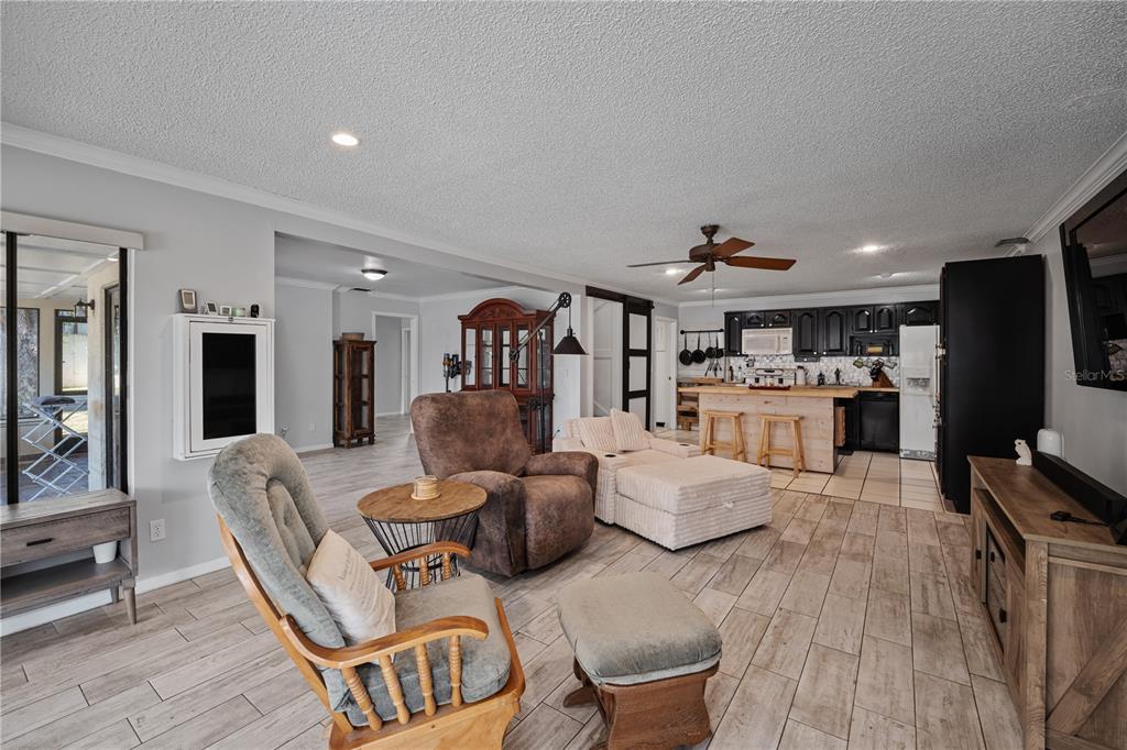 An open-concept living room and kitchen featuring wood-look tile flooring and a wooden island — 11210 ELDERBERRY COURT, CLERMONT, FL