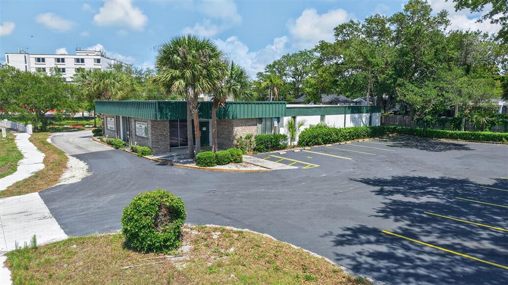 An exterior view of a single-story commercial building with a parking lot and palm trees — 2039 INDIAN ROCKS ROAD S, LARGO, FL