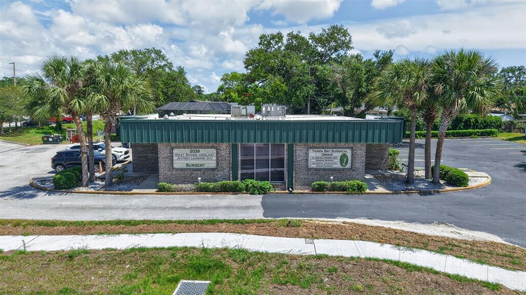 A single-story commercial building with a green roof and brick facade sits in a parking lot — 2039 INDIAN ROCKS ROAD S, LARGO, FL
