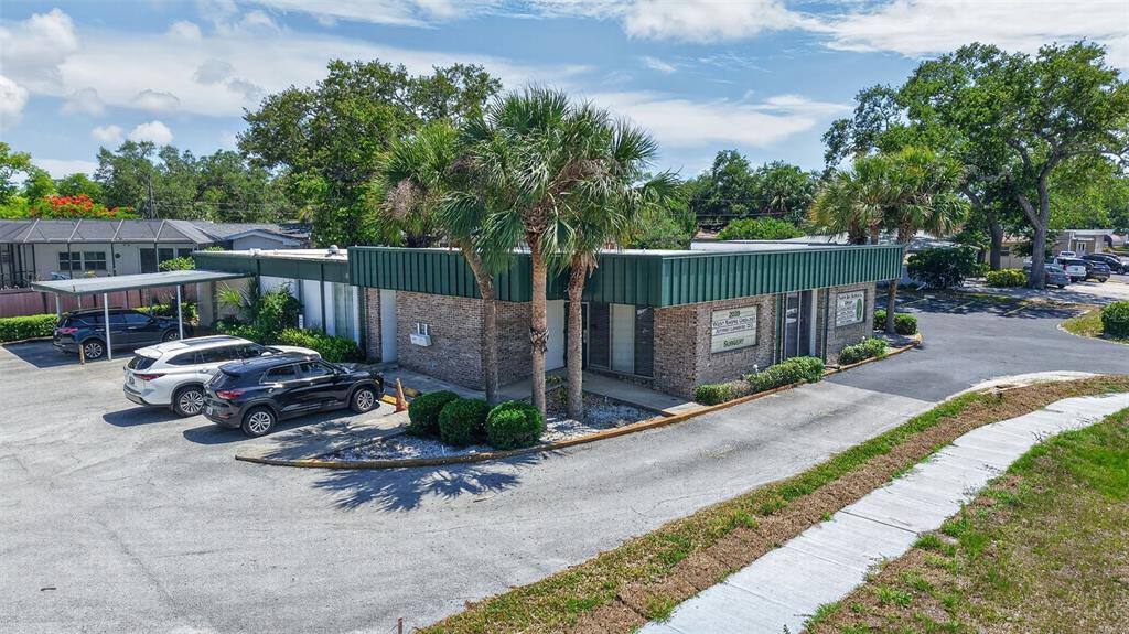 An exterior view of a single-story brick commercial building with a green metal roof — 2039 INDIAN ROCKS ROAD S, LARGO, FL