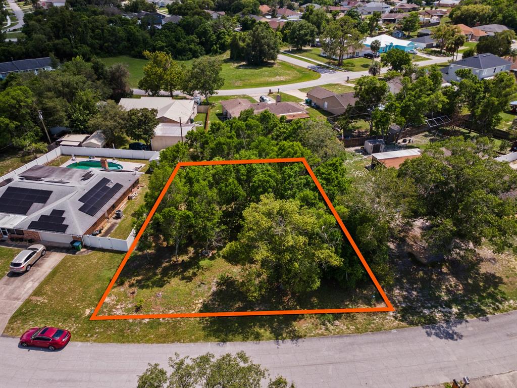 An aerial view shows a vacant, tree-covered residential lot outlined in orange — 1041 FEATHER DRIVE, DELTONA, FL