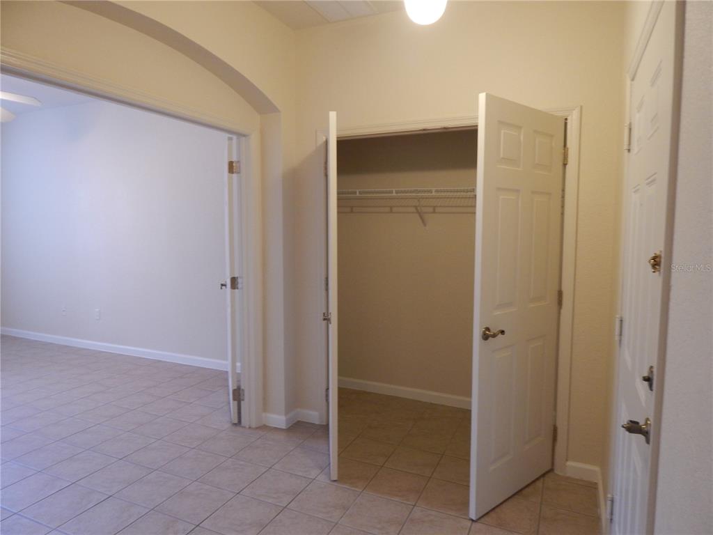 A room with tile flooring, an open closet, and an arched doorway leading to another room — 3300 WHITESTONE CIRCLE UNIT 107, KISSIMMEE, FL