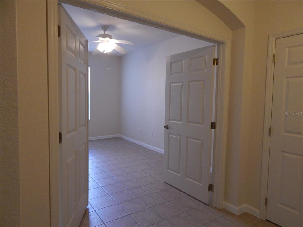 A room with tiled flooring and a ceiling fan is visible through double doors — 3300 WHITESTONE CIRCLE UNIT 107, KISSIMMEE, FL