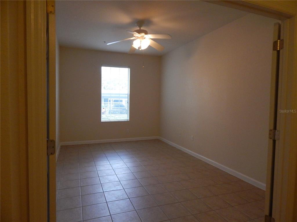 An empty room features light-colored walls, a ceiling fan, and tiled flooring — 3300 WHITESTONE CIRCLE UNIT 107, KISSIMMEE, FL