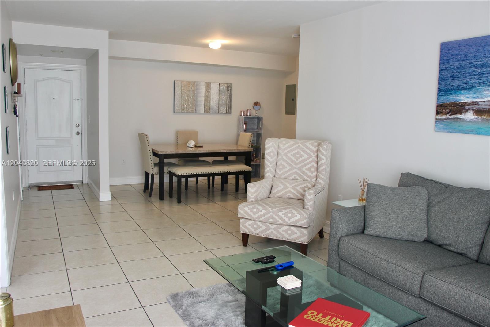 A living and dining area features tile floors, a gray sofa, and a patterned armchair — 2501 Douglas Rd # 304, Miami FL 33133, MIAMI, FL