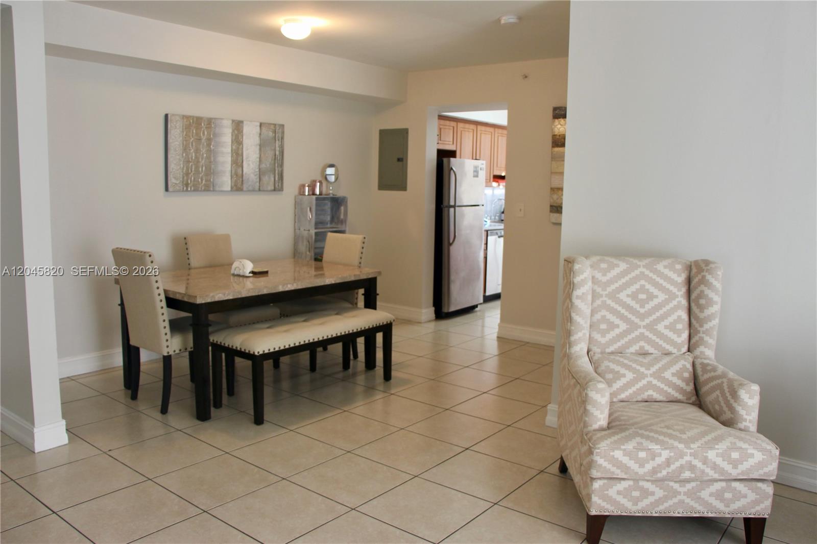 A dining area with a stone-topped table and a patterned armchair on tiled floors — 2501 Douglas Rd # 304, Miami FL 33133, MIAMI, FL
