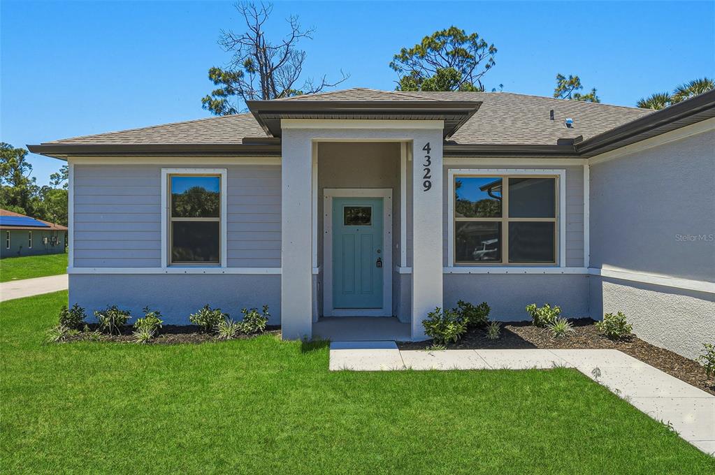 A single-story house with gray siding, a light blue front door, and a concrete walkway — 2822 YAMADA LANE, NORTH PORT, FL