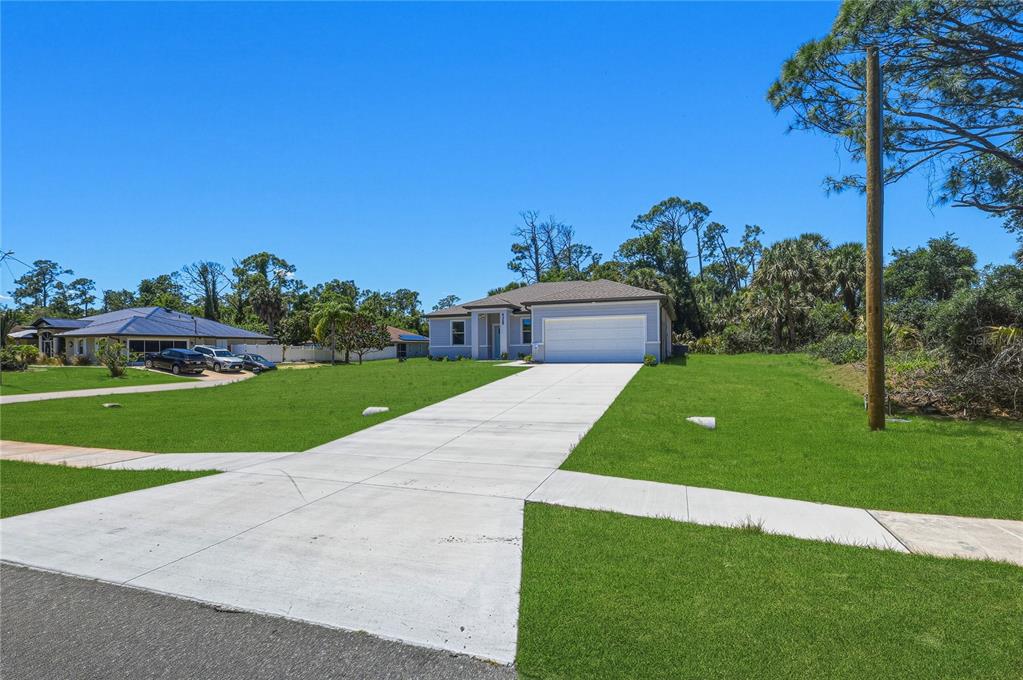 A single-story house with a white garage and a concrete driveway sits on a lawn — 2822 YAMADA LANE, NORTH PORT, FL