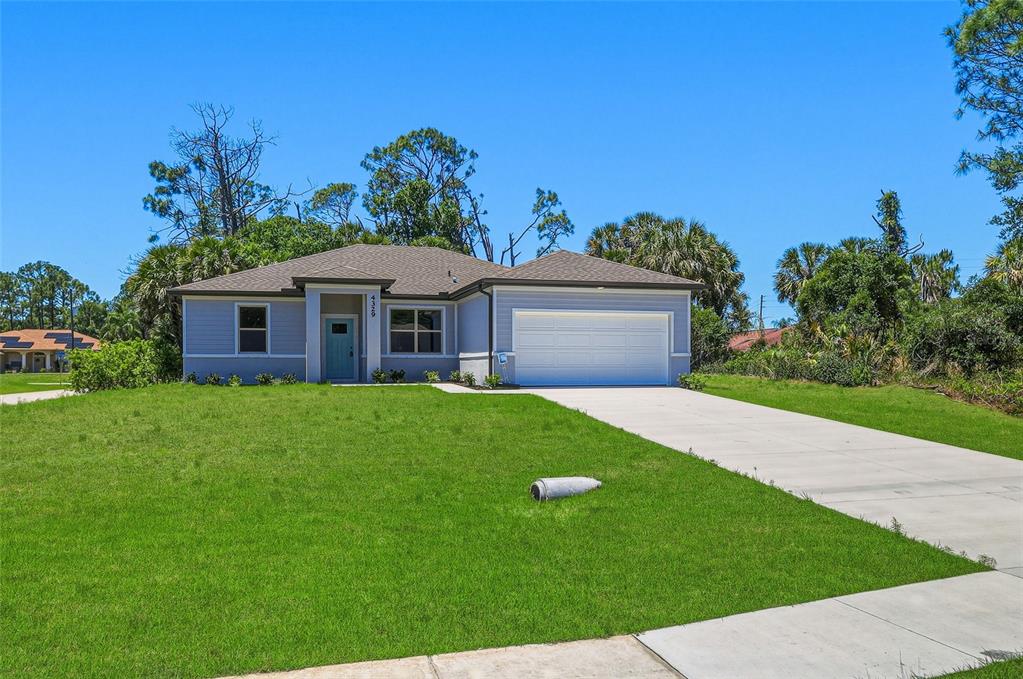A single-story house with light blue siding, a white garage door, and a concrete driveway — 2822 YAMADA LANE, NORTH PORT, FL